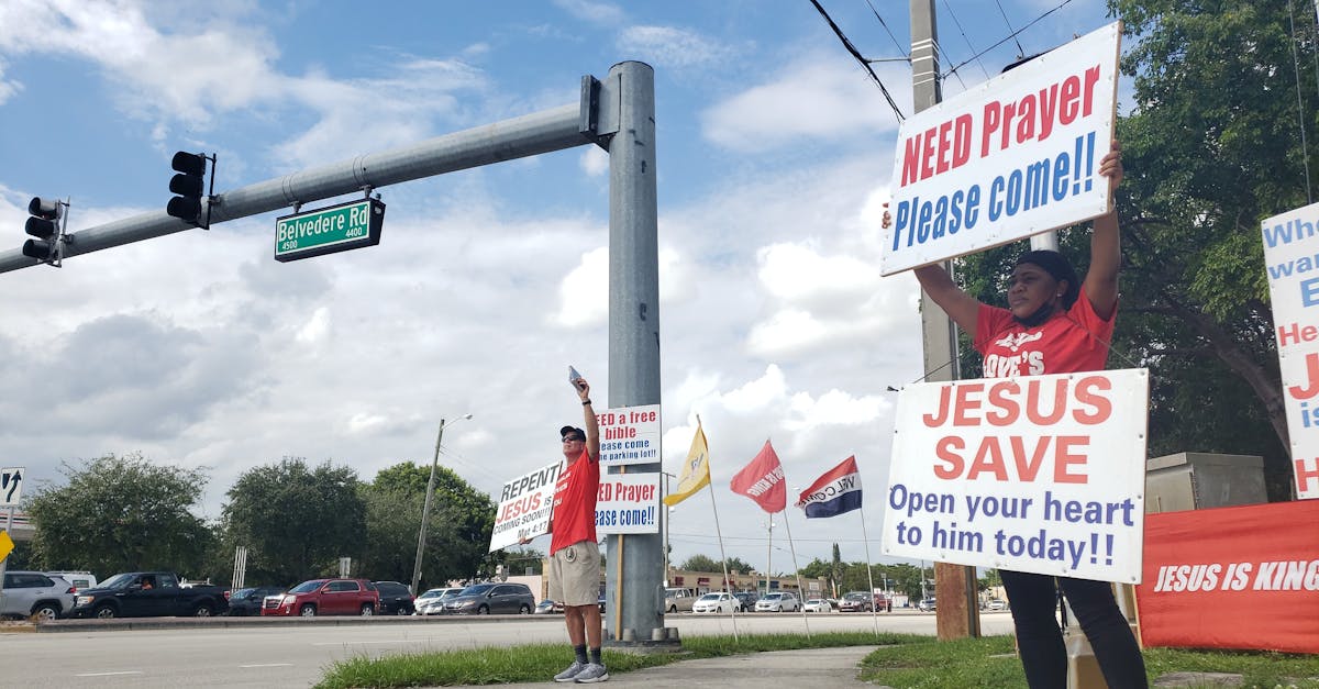 Group holding religious signs promoting prayer and faith on a city street corner.